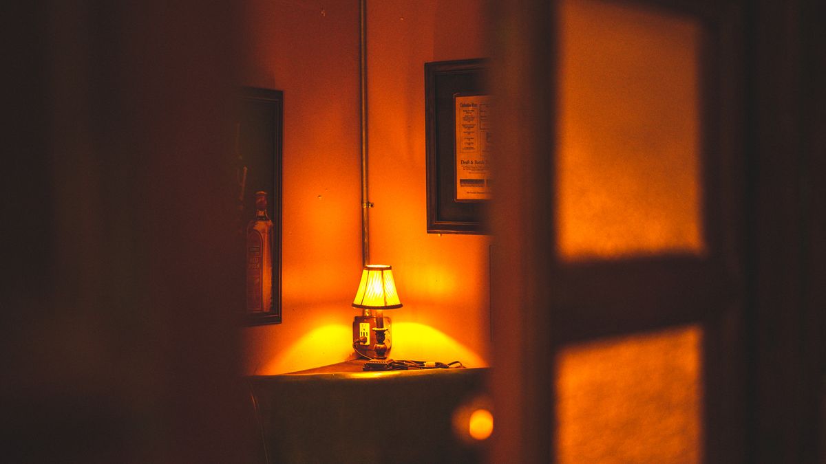Lampe à la lumière chaude et dorée éclairant un coin de pièce dans la pénombre