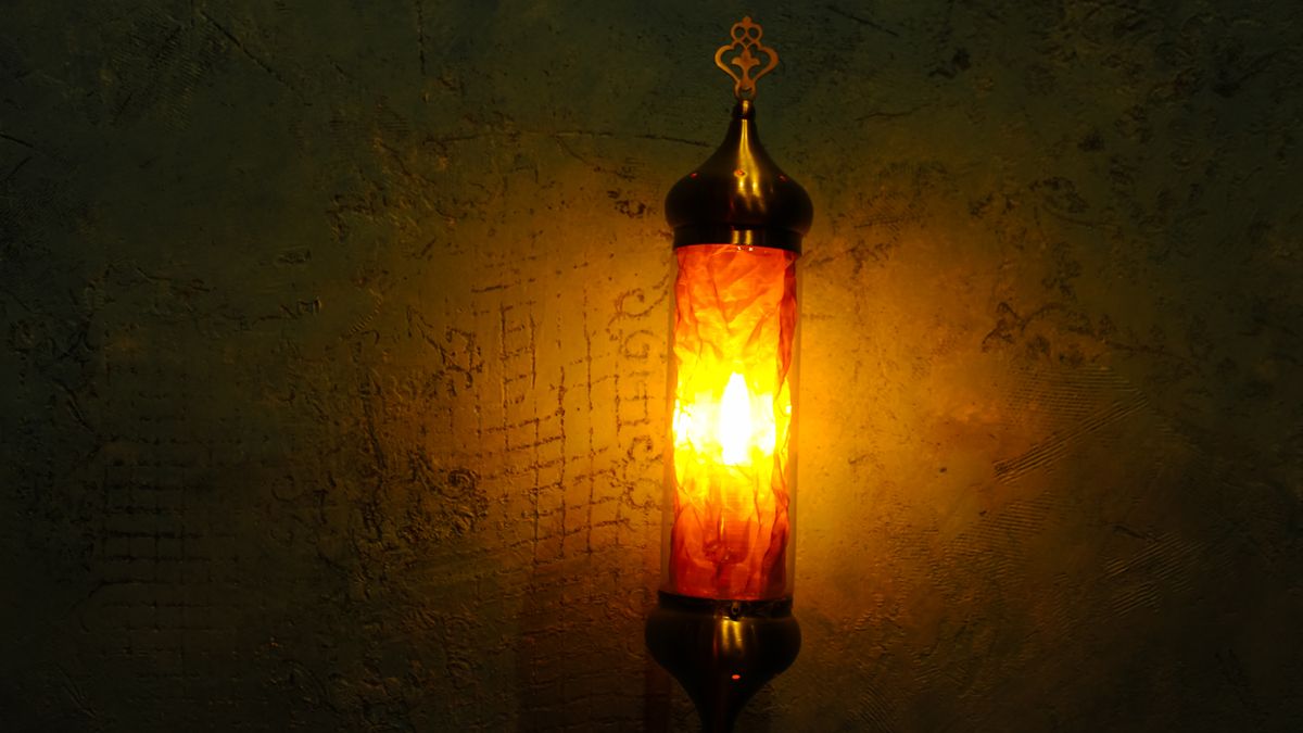 Applique murale au diffuseur doré projetant une lumière chaude sur un mur