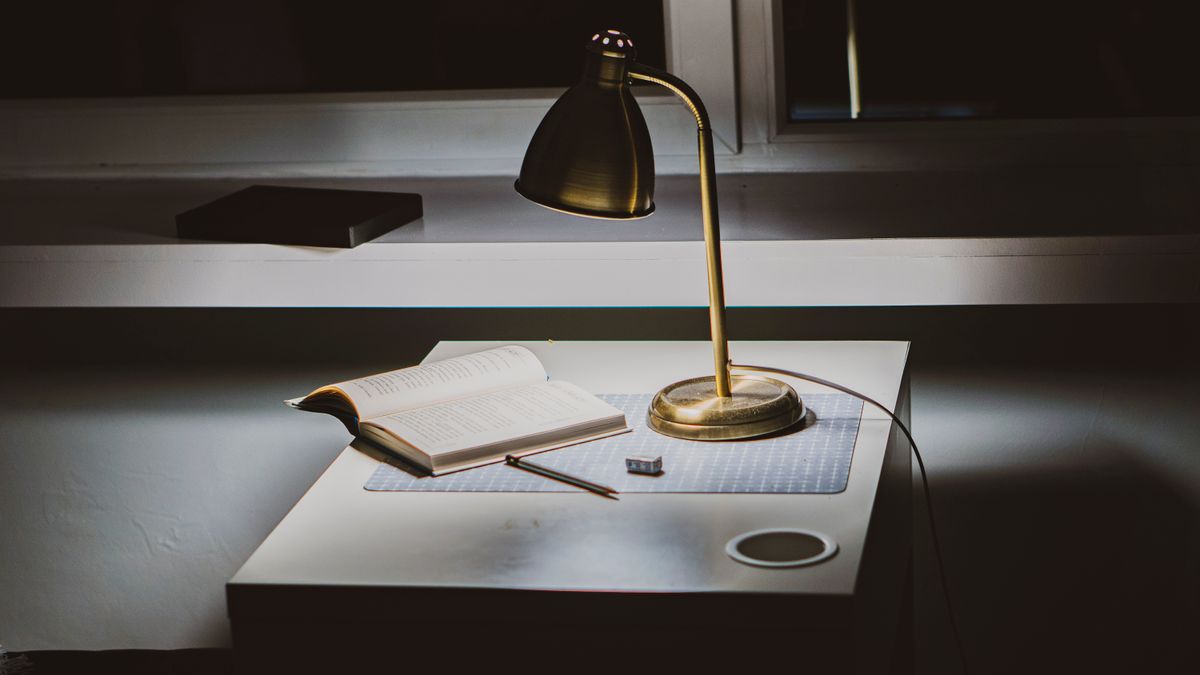 Lampe de bureau dorée allumée sur un plan de travail
